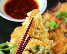 chopsticks holding up food with sauce on the side