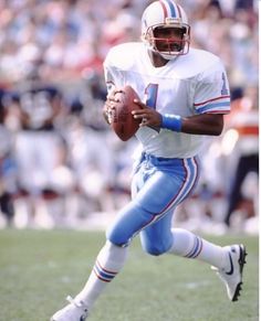 a football player running with the ball in his hand and people watching from the stands