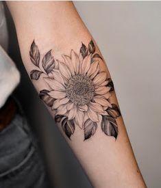 a woman's arm with a sunflower tattoo on it