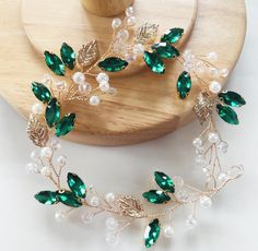 Adorn your hair with the enchanting beauty of this Handmade Emerald Crystal and Gold Leaf Hair Vine, a luxurious accessory that blends nature-inspired elegance with artisan craftsmanship.  Featuring radiant emerald-green crystals intertwined with delicate gold leaves, this hair vine brings a touch of sophistication to any look.  The flexible design allows it to be styled in various ways, from wrapped around an updo to cascading along loose waves.  Perfect for weddings, formal events, or special Elegant Green Fitted Headpiece, Elegant Fitted Green Headpiece, Luxury Green Elegant Headpieces, Elegant Green Hair Accessories For Wedding, Emerald Green Hair Accessories, Emerald Green Hair, Autumn Bridal, Occasion Hats, Crystal Hair Vine