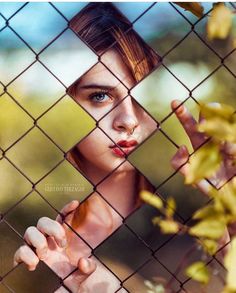 a girl looking through a fence with her hand on the fence and an inscription in arabic