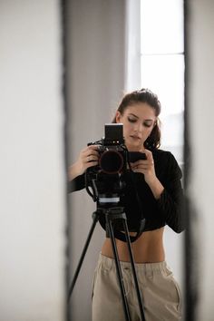 a woman taking a photo in front of a mirror with a camera on a tripod