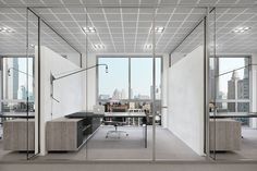 an office with glass walls and desks in front of large windows overlooking the city