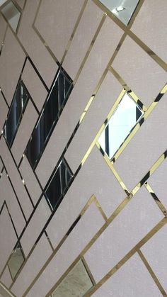 a mirror that is on the side of a wall with gold trimmings and geometric shapes