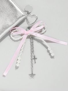 a cross and pearls key chain with a pink ribbon tied around it, next to a silver purse