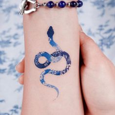 a person with a blue snake tattoo on their left arm and the number 3 painted on her wrist