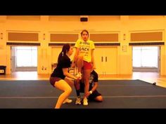 three women in a gym with one kneeling down and the other standing on her knees