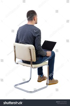 a man sitting in a chair with his laptop on his lap and looking at the screen