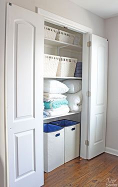 an open closet with white baskets and folded towels on the shelves, next to two doors