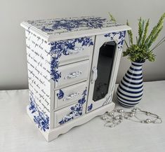 a blue and white cabinet next to a vase with flowers in it on a table