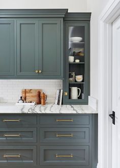 a kitchen with green cabinets and marble counter tops