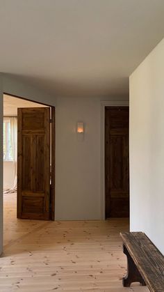 an empty room with wood flooring and wooden door leading to another room in the background