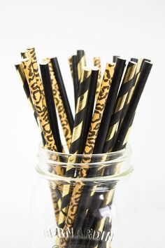 several black and gold striped straws in a jar