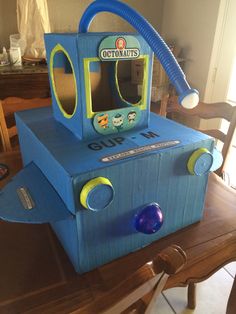 a blue toy machine sitting on top of a wooden table