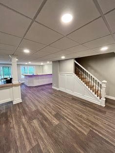 an empty living room with hard wood flooring and white railings on the stairs