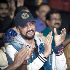 a man with his hands in the air while wearing a baseball cap and denim vest