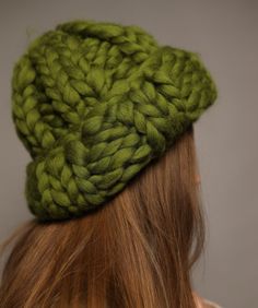 a woman with red hair wearing a green knitted hat on top of her head