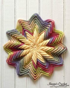 a crocheted flower is hanging on a white wooden wall with the words magic's closet written below it