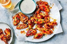 chicken wings on a plate with dipping sauce and a glass of beer next to it