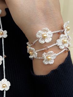 a close up of a person wearing two bracelets with flowers on the side and pearls attached to them