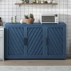 a kitchen with blue cabinetry and white tiled walls, along with a microwave on top of it