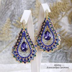 a pair of earrings with blue and green beading on top of each earring