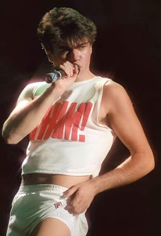 a male in a white tank top and green trunks holding a microphone to his ear