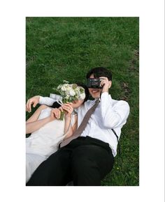 a man and woman laying in the grass with their hands on each other's heads