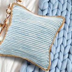 a blue and white pillow sitting on top of a bed next to a blue blanket