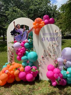 there is a birthday sign with balloons and flowers in the grass next to it that says happy birthday gabby