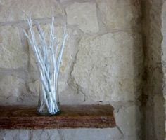 there is a vase with branches in it on the ledge next to a stone wall