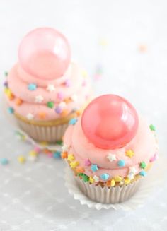 two cupcakes with pink frosting and sprinkles on top are shown