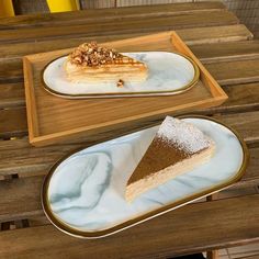 two plates with desserts on them sitting on top of a wooden table next to each other