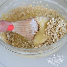 a wooden spoon in a bowl filled with oatmeal and granola flakes