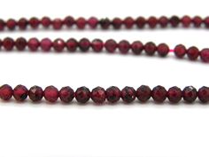 red glass beads are lined up on a white surface