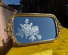 there is a mirror with flowers on it in front of a yellow table cloth covered surface