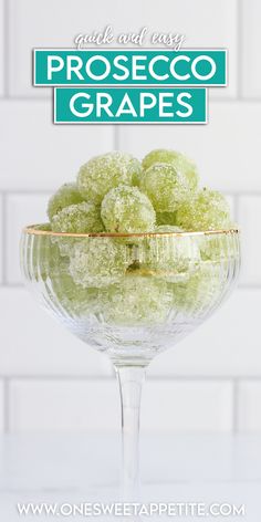 a glass bowl filled with green grapes on top of a table next to a white brick wall