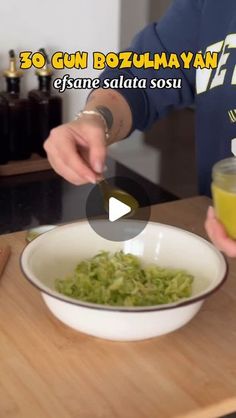 a person holding a spoon over a bowl of food on top of a wooden table