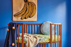 a baby sleeping in a crib with a painting on the wall behind it and a banana hanging above