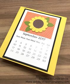 a calendar card with a sunflower on it sitting on top of a wooden table