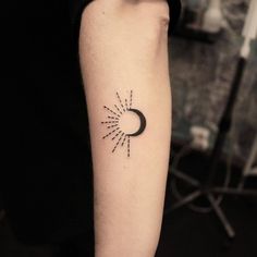 a small sun and moon tattoo on the left arm with black lines coming out of it