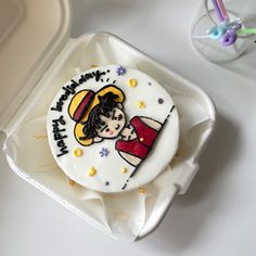 a decorated birthday cake sitting on top of a white tray next to a plastic container