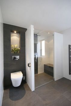 a white toilet sitting next to a walk in shower under a bathroom mirror above a sink