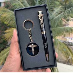 a key chain with a medical symbol on it and a pen in the box next to it