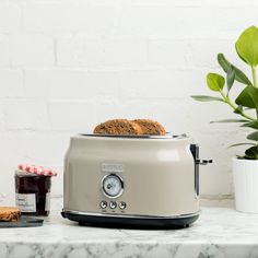 a toaster sitting on top of a white counter next to a potted plant