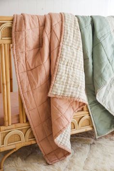 three blankets are folded on top of a wicker crib