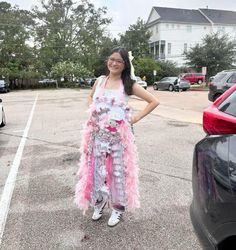 a woman standing in the middle of a parking lot wearing a pink and white dress