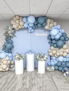 an arch made out of balloons and flowers in front of a wall with two vases