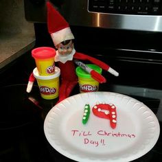 an elf is sitting next to a plastic plate with food on it and the words til't christmas day written on it