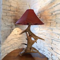 an antler lamp sitting on top of a wooden table next to a brick wall